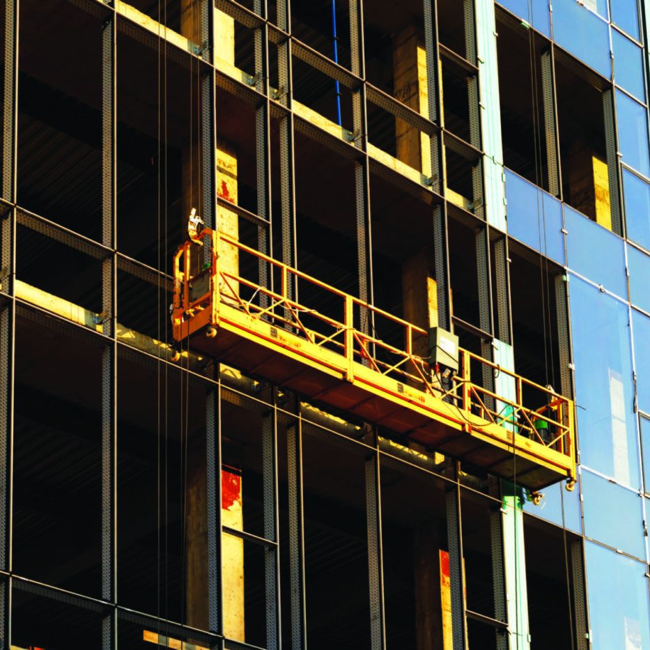 Suspended construction craddle near wall of hightower building with insulation and ventilated facade on construction site. Engineering urban background.